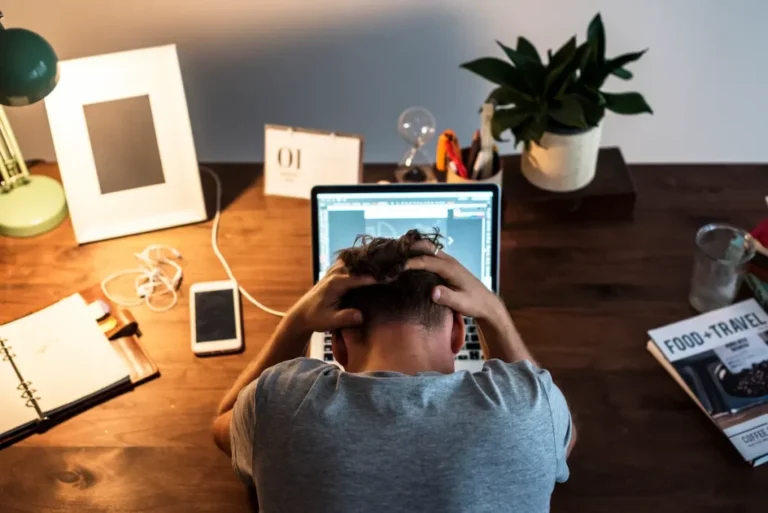 Homem diante de um notebook com expressão de cansaço